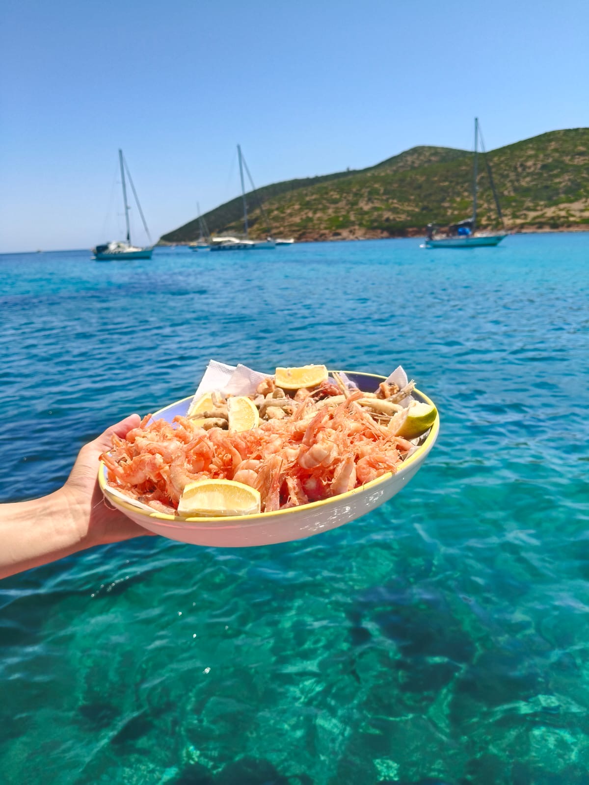 Piatto di gamberi freschi appena pescati con il mare turchese sullo sfondo